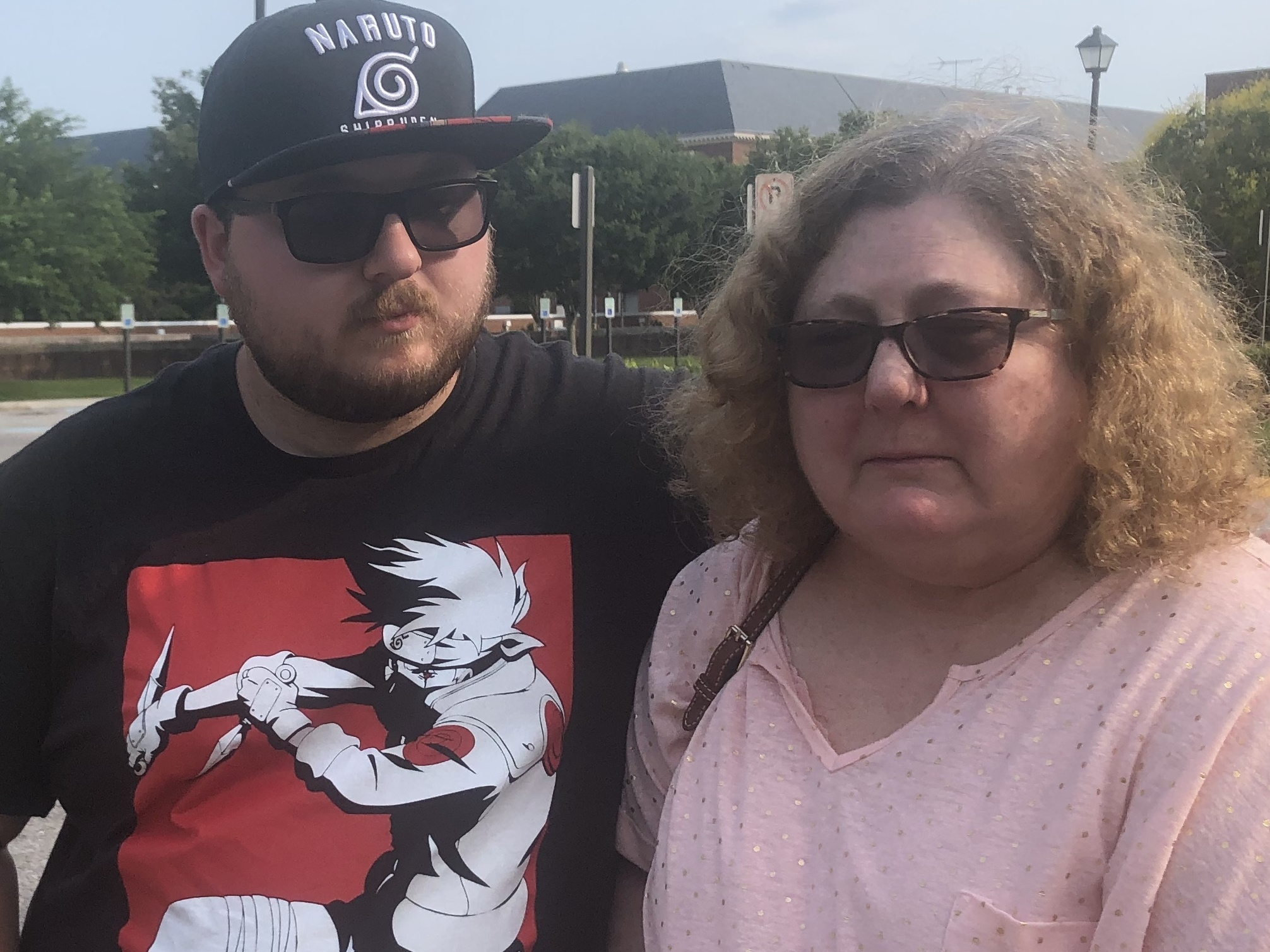 Christi Dewar, a survivor of the Virginia Beach mass shooting, stands with her son, Charles Dewar III, next to the office complex where a gunman killed 12 and injured several others on Friday. (NPR)