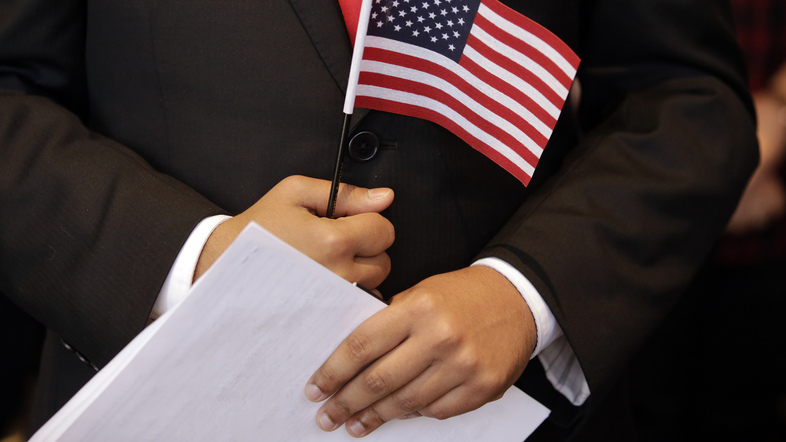A newly sworn-in U.S. citizen holds a U.S. flag and documents during a naturalization ceremony in 2018 at the John F. Kennedy Presidential Library and Museum in Boston. (Steven Senne/AP)