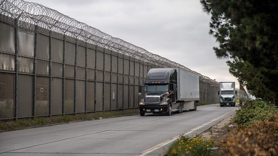 Cargo trucks pass the secondary fence that divides the United States and Mexico in Otay Mesa, Calif., on May 31. Vice President Pence held a meeting with Mexican officials on Wednesday over threats to raise tariffs on that country. (Ariana Drehsler/AFP/Getty Images)