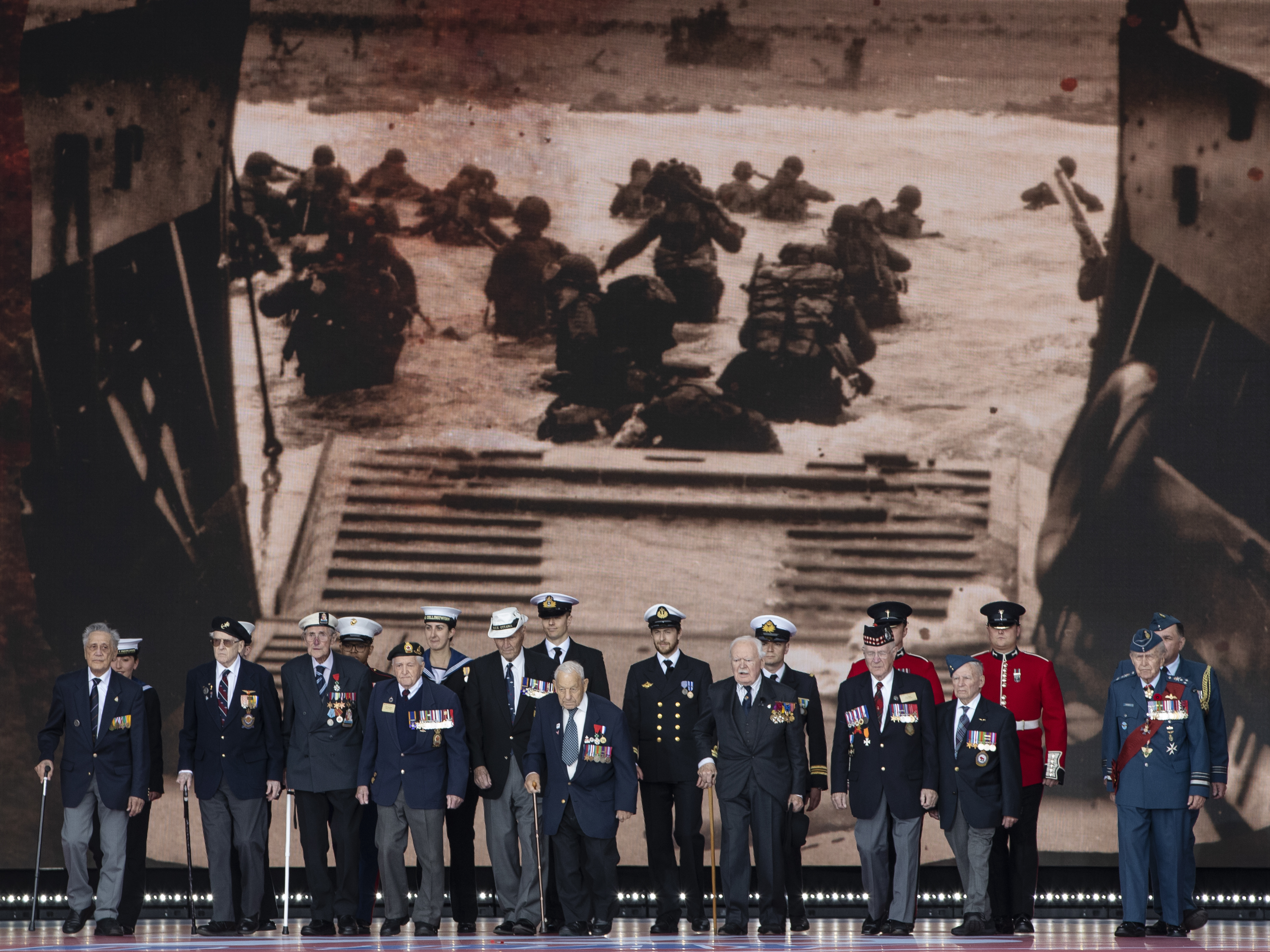Veterans stand in front of a 1944 image of their comrades wading onto the beaches of France during D-Day commemorations in Portsmouth, England. Leaders of 16 countries involved in World War II joined Queen Elizabeth II at the ceremony on Wednesday. (Getty Images)