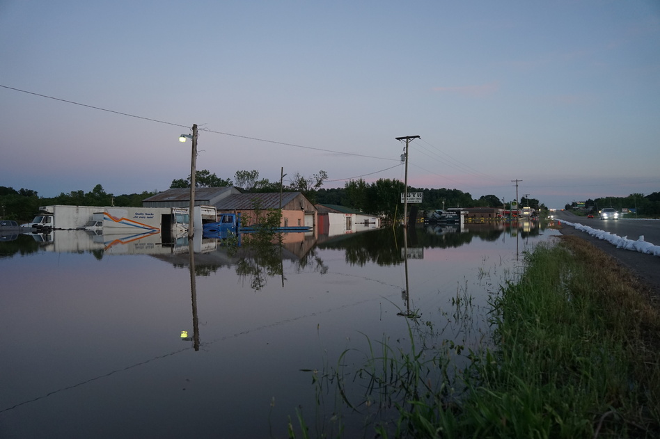 Floodwaters from the Arkansas River line either side of a road in Russellville, Ark., in late May, engulfing businesses and vehicles. (Nathan Rott/NPR)