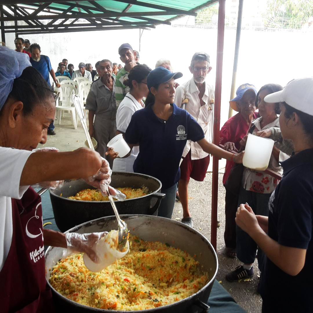 Men, women and children line up for free lunch at a soup kitchen in Maracaibo, Venezuela. The meal consists of a bottle of milk and a few scoops of rice mixed with eggs and vegetables. (John Otis for NPR)