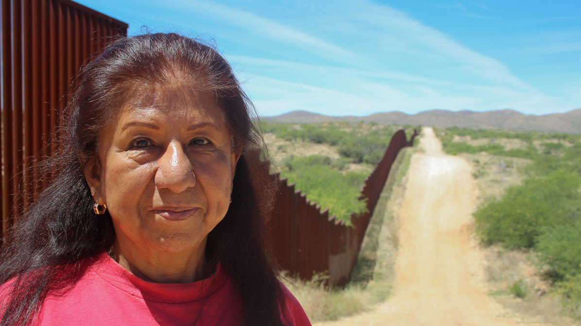 Maria Ochoa poses by the Arizona-Mexico border wall, south of Tucson, Ariz. (StoryCorps)