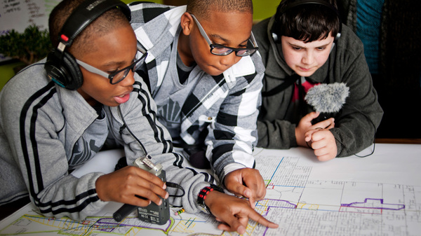 Students podcasts from the Steel City Academy in Gary, Indiana, Erin Addison (left), Evan Addison, and Andrew Arevalo (right), look over a planning map of the City of Gary.