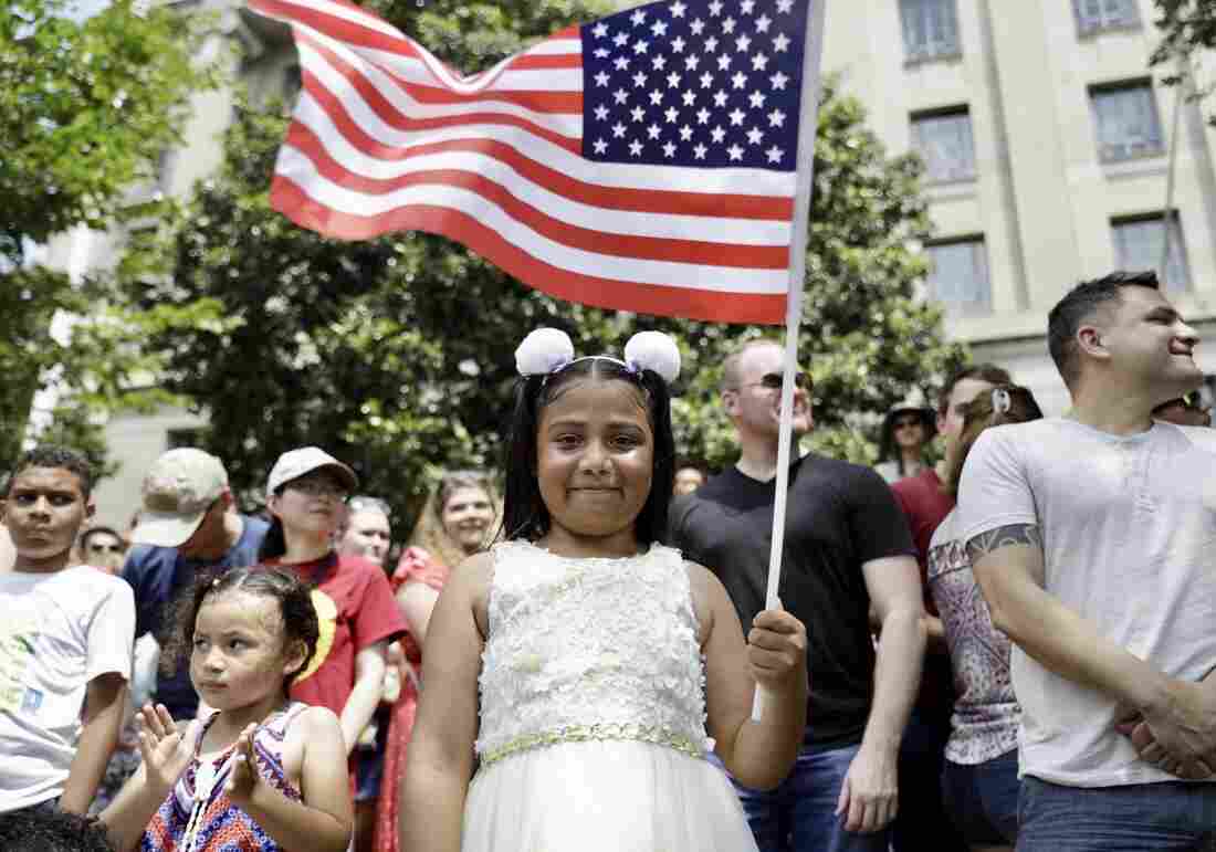 A girl stands waving a flag on the streets of D.C. during the National Independence Day Parade.