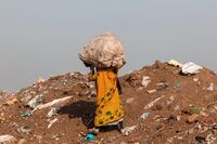 A trash picker carries a sack of recyclable materials she collected at the Ghazipur landfill in the east of New Delhi.