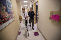 Dr. Mary Rice walks with Michael Howard at a Beth Israel Deaconess HealthCare clinic in Chealsea, Mass, as they test his oxygen levels with the addition of oxygen from a portable tank. He has COPD, a progressive lung disease that can be exacerbated by heat and humidity.