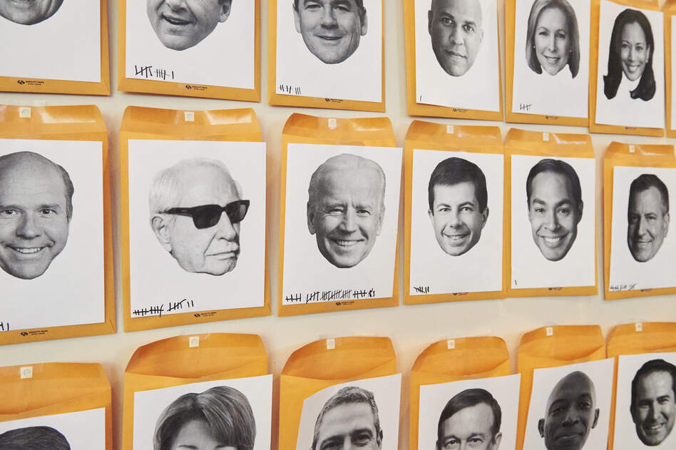 A wall titled "Who's The Next To Drop Out?" with faces of the Democratic candidates running for president in the 2020 election is displayed during the Netroots Nation conference at the Pennsylvania Convention Center in Philadelphia on Saturday. (Natalie Piserchio for NPR)