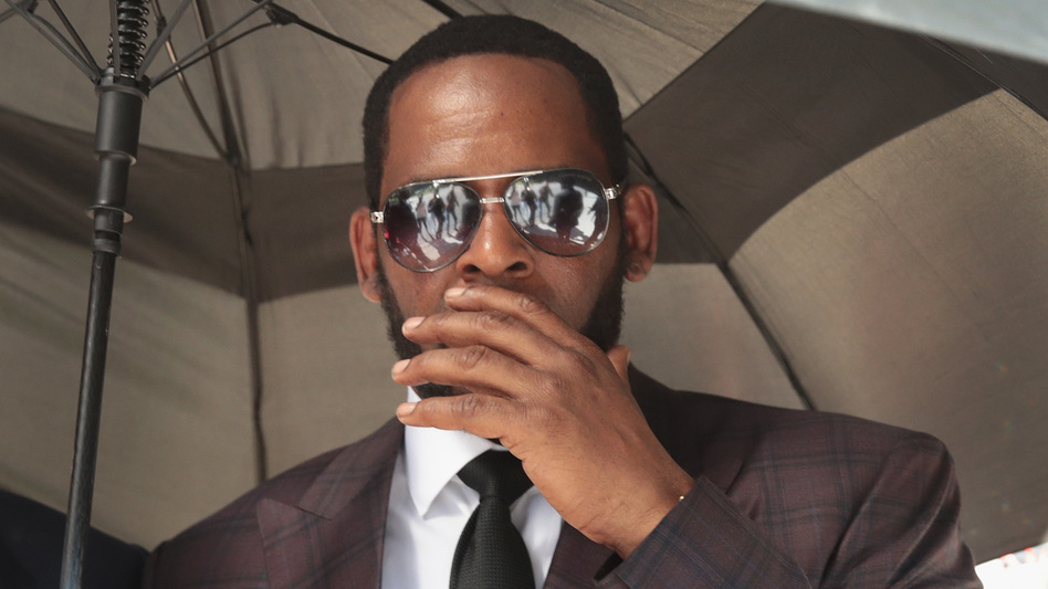 R&B singer R. Kelly covers his mouth as he speaks to members of his entourage as he leaves the Leighton Criminal Courts Building following a hearing on June 26, 2019 in Chicago. (Scott Olson/Getty Images)