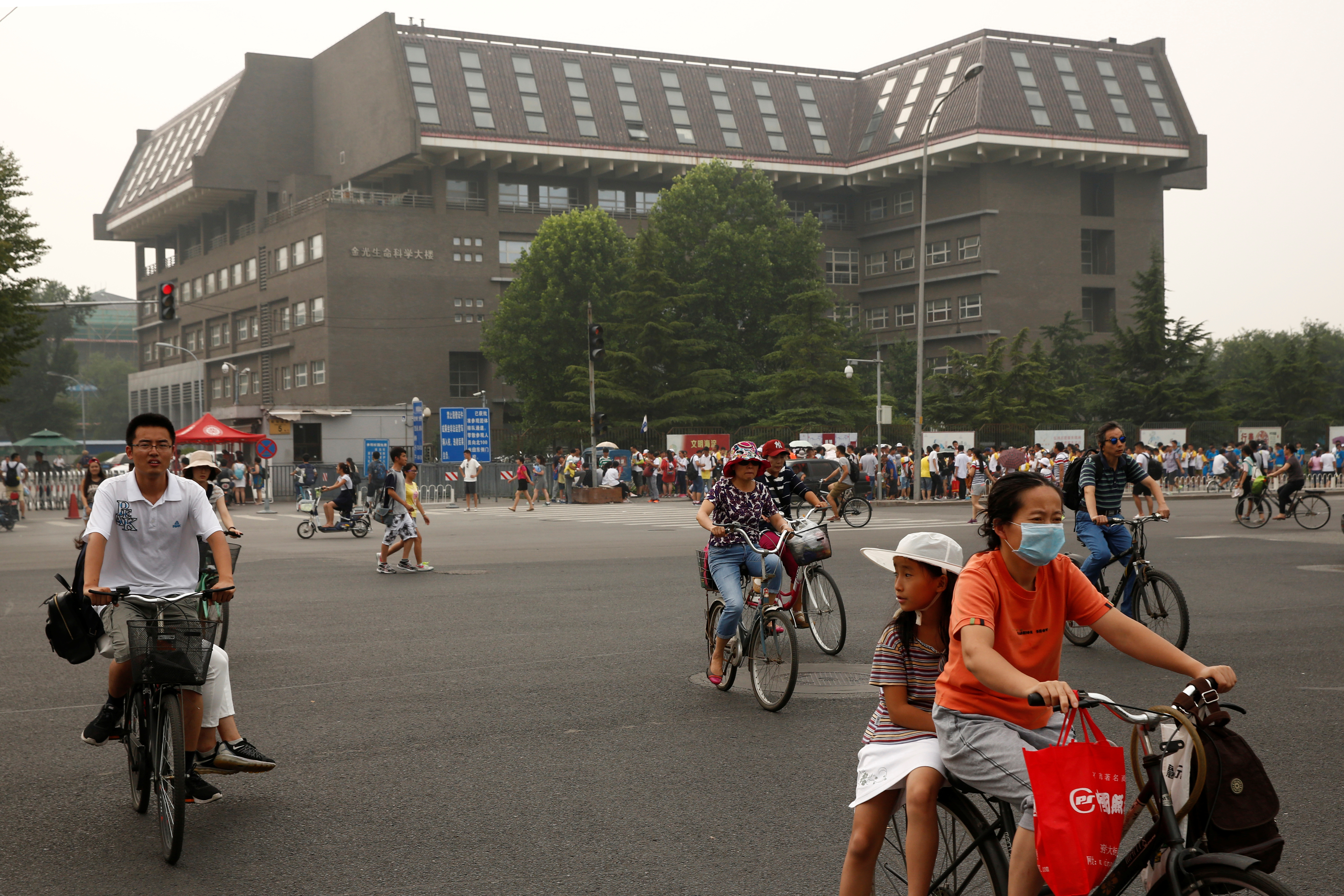 People cycle past a building at Peking University in Beijing in 2016. The university hosts Yenching Academy, a prestigious graduate studies program.