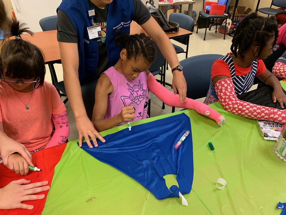 At Nashville's "High Five" camp, 12-year-old Priceless Garinger (center), whose right side has been weakened by cerebral palsy, wears a full-length, bright pink cast on her left arm — though that arm's strong and healthy. By using her weaker right arm and hand to decorate a cape, she hopes to gain a stronger grip and fine motor control.