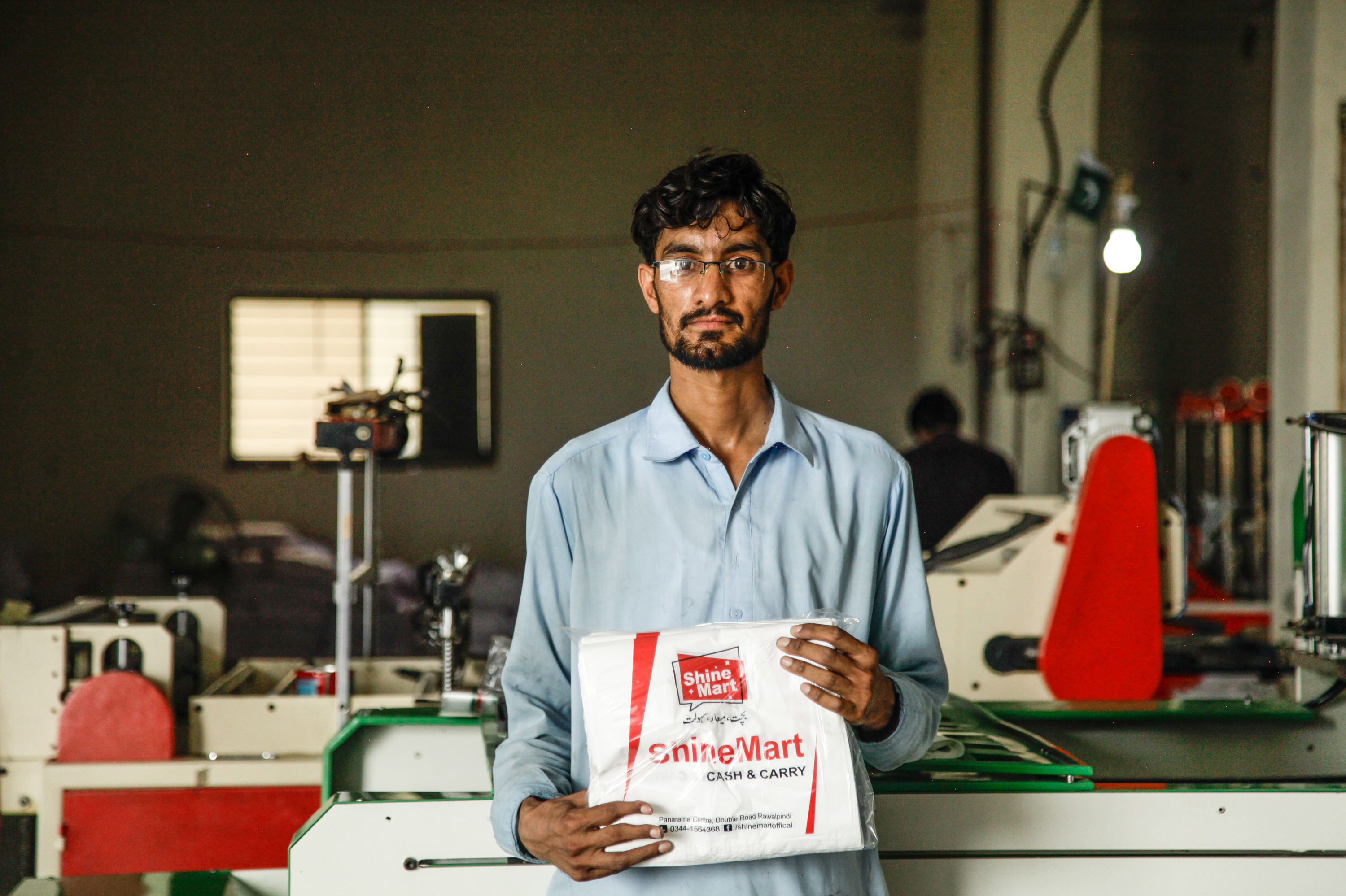 Mohammad Zaheer holds up bags freshly stamped with supermarket slogans. He says he's worried about his future after the plastic bag ban begins. He says that if he has to find another job, "it will be difficult, because there is much unemployment."