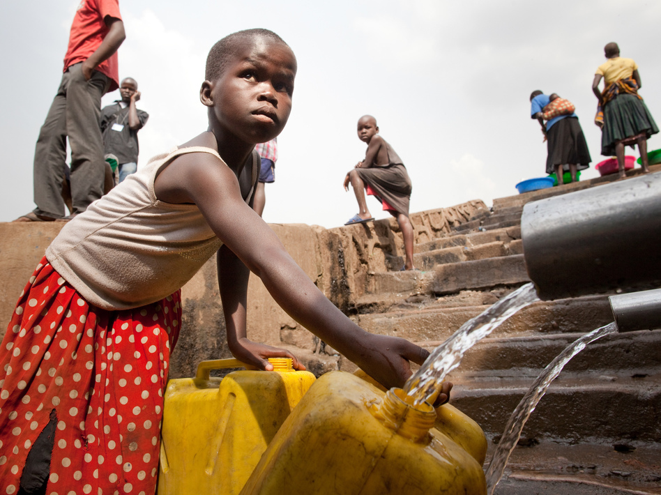 A child in a neighborhood in Kampala, Uganda, fills a container with water.