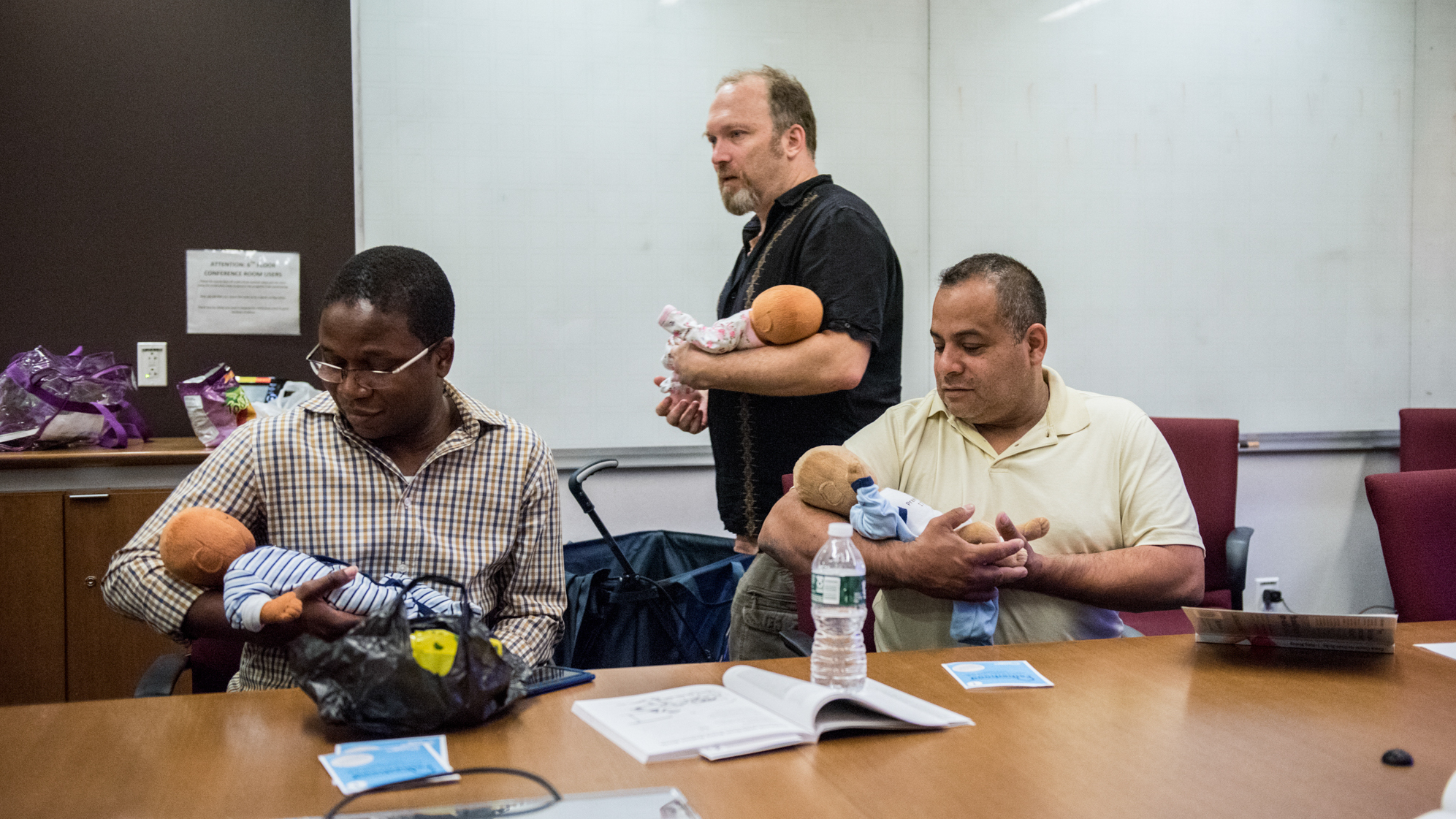 Joe Bay (center), coach of a New York City "Bootcamp for New Dads," instructs Adewale Oshodi (left) and George Pasco in how to cradle an infant for best soothing.