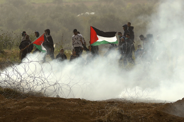 Palestinian protesters wave national flags as they demonstrate to mark the first anniversary of the "March of Return" protests. Tens of thousands of Gazans gathered along the Israeli border to mark a year since protests and clashes erupted there, days ahead of an Israeli general election.