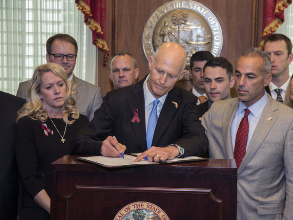 Florida Gov. Rick Scott signs the Marjory Stoneman Douglas Public Safety Act in the governor's office at the Florida State Capitol in Tallahassee, on March 9, 2018.