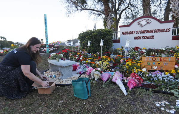 Suzanne Devine Clark, an art teacher at Deerfield Beach Elementary School, places painted stones at a memorial outside Marjory Stoneman Douglas High School during the one-year anniversary of the school shooting on Feb. 14, 2019, in Parkland, Fla. The state passed its red flag law in 2018 after the shootings at the high school.