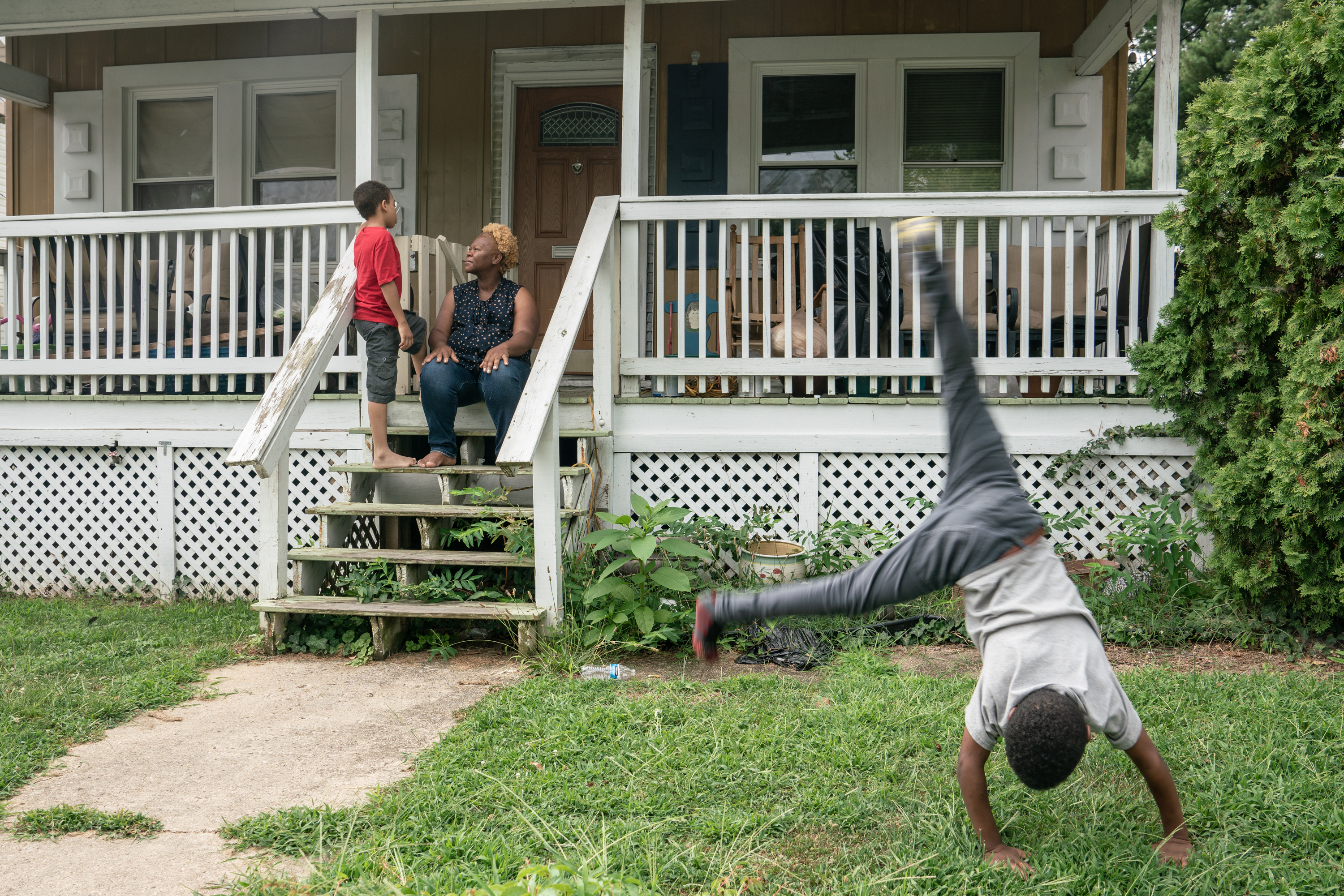 Bridget Desmukes shares time with her son Jonathan on the front porch of their home in Washington, D.C., while his brother, Jeffrey, does cartwheels. The boys say they're very excited that the coming baby's going to be a boy, too.