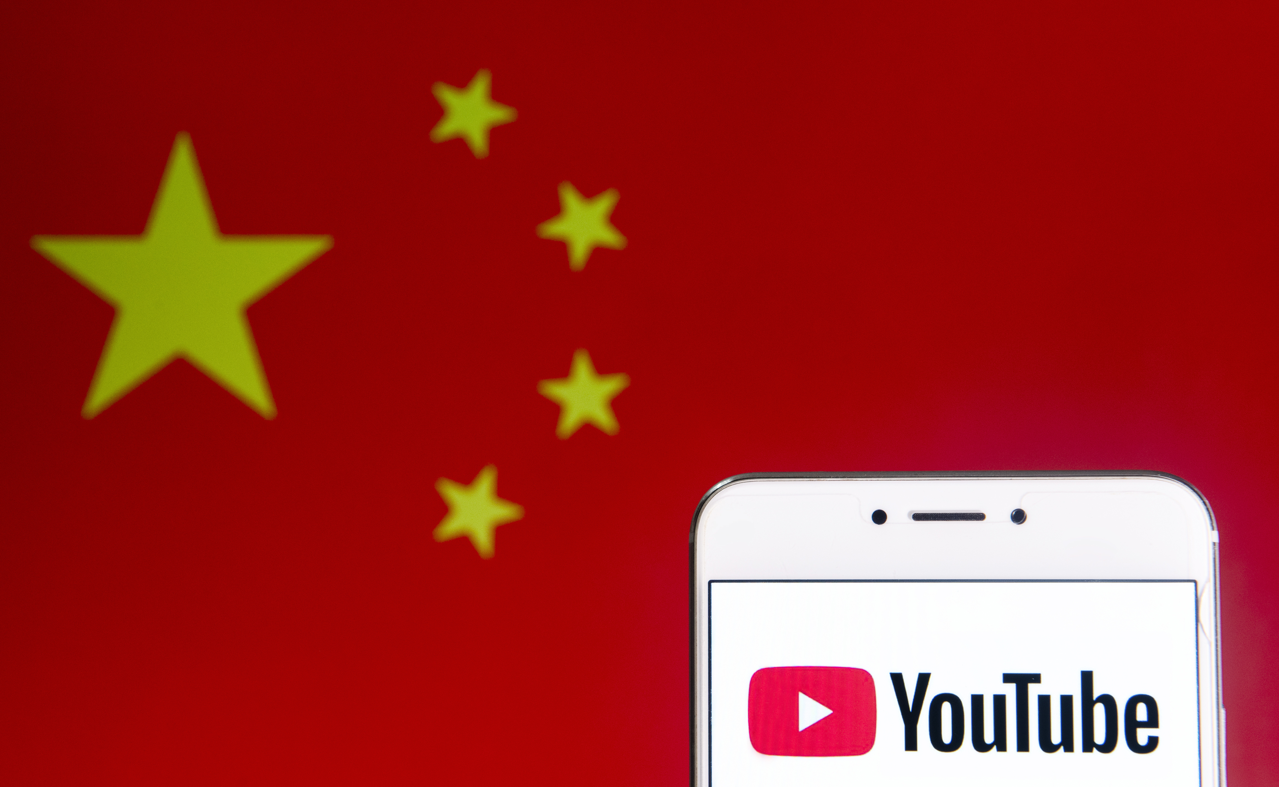 An illustration of the video-sharing website Youtube logo and an Android mobile device with People's Republic of China flag in the background. (LightRocket via Getty Images)
