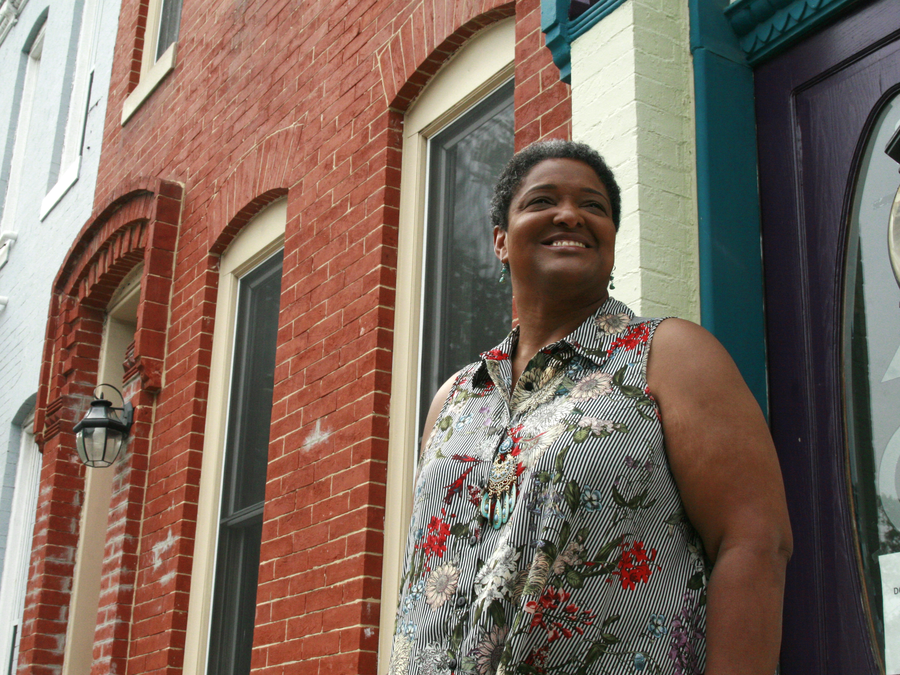 Jeanetta Churchill stands outside of her Baltimore row house. She says she has to keep her air running constantly in the summer in order to manage her bipolar disorder. (NPR)