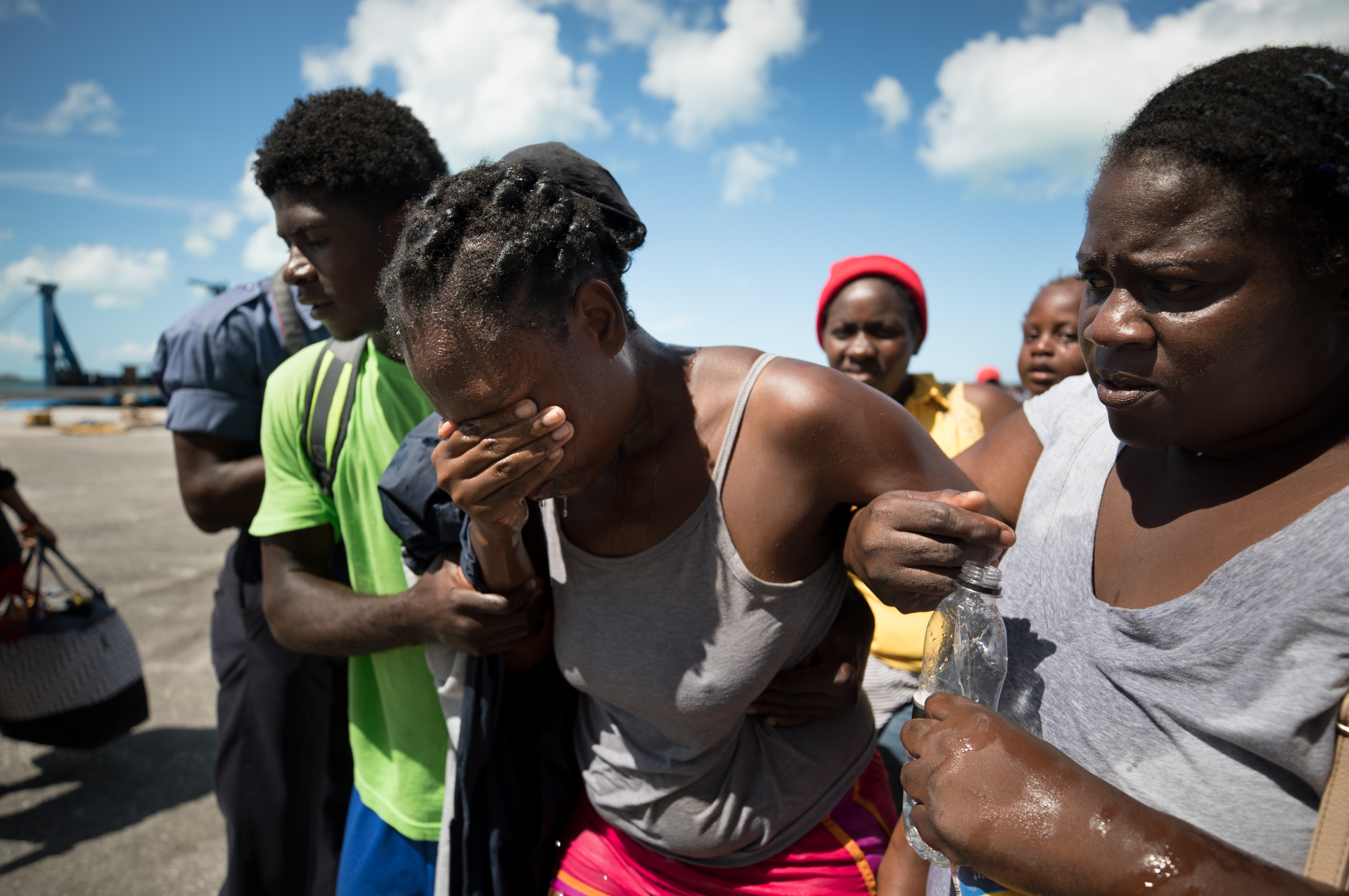 Nicole Guillaume, who was nursing her 2-year-old son while waiting with several hundred other Haitians and Bahamanians at the port of Marsh Harbour, fainted in the heat. (Cheryl Diaz Meyer for NPR)