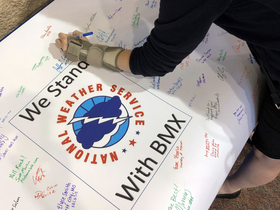 Christina Crowe signs a poster in support of the National Weather Service office in Birmingham, Ala., during a convention of the National Weather Association. (Jay Reeves/AP)