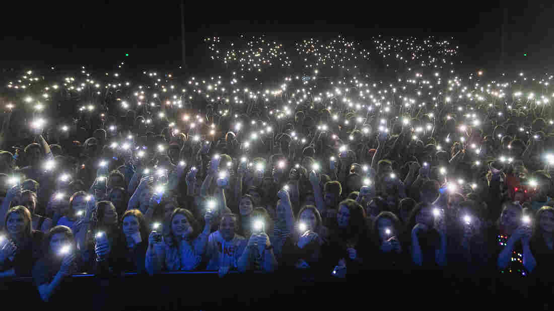 Fans hold up cell phones during a concert.