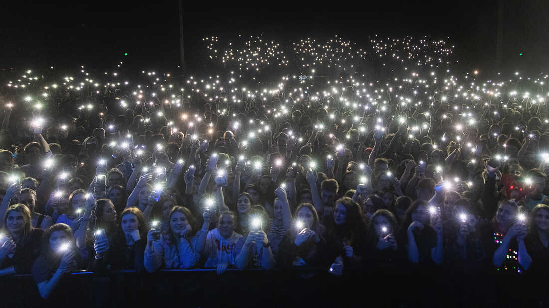 Fans hold up cell phones during a concert.