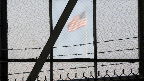 An NPR investigation finds that the military court and prison at Guantánamo Bay, Cuba, have cost taxpayers billions of dollars, with billions more expected. (Above) An American flag is seen through the war crimes courtroom at the U.S. naval base at Guantánamo Bay on Oct. 17, 2012.