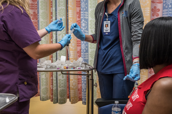 Registered nurses Bonnie Carroll (left) and Brooke Ryan (center), draw blood from Gray.