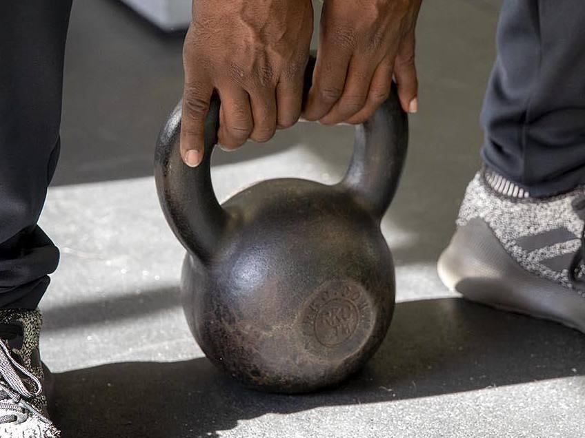 Justice Williams demonstrates how to lift a kettlebell. (WBUR)