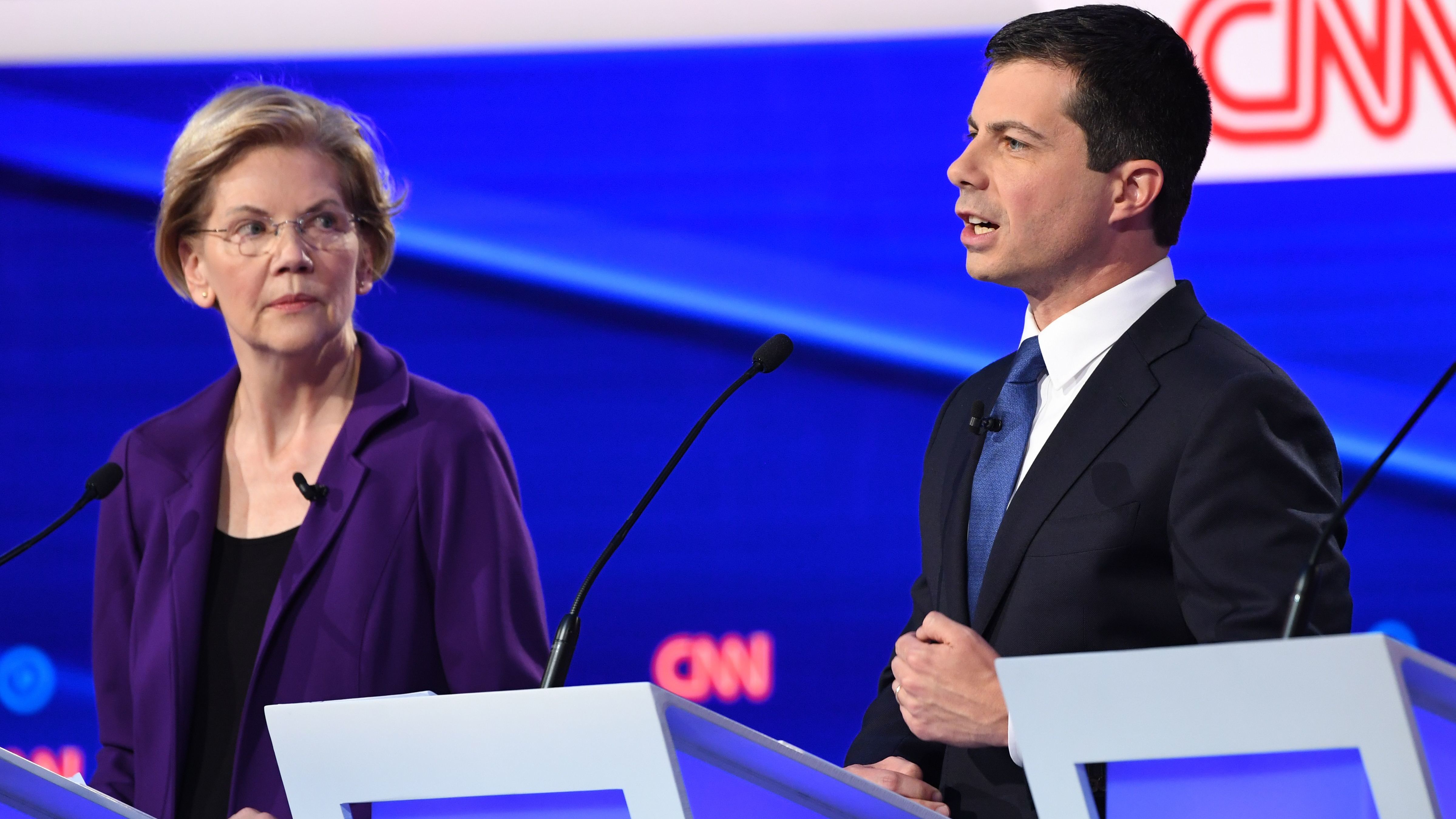 Massachusetts Sen. Elizabeth Warren looks on as South Bend, Ind., Mayor Pete Buttigieg speaks during Tuesday's Democratic presidential debate. Warren's policy positions were described as unrealistic and expensive by her rivals in the Democratic debate. (AFP via Getty Images)