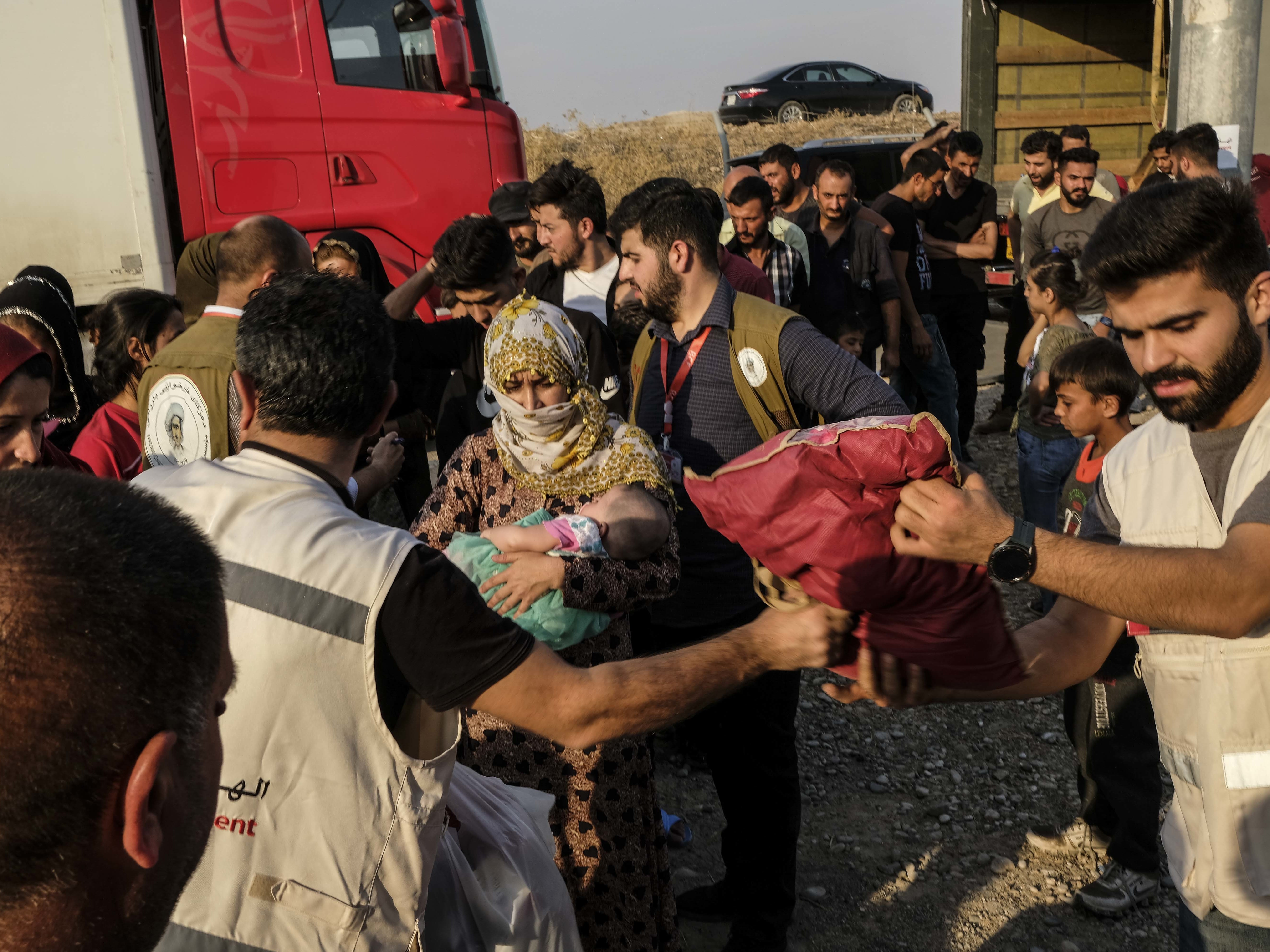 Syrians fleeing the Turkish incursion in northeastern Syria receive bedding materials as they arrive at a camp in Dohuk, Iraq, on Thursday. (Getty Images)