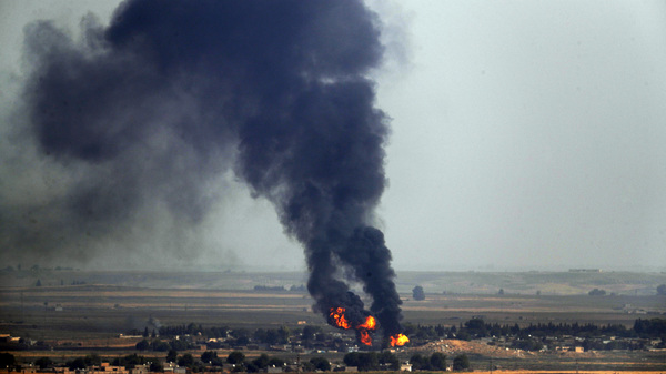 In this photo taken Thursday, flames and smoke billow from a fire on a target in Ras al-Ayn, Syria. This is the result of shelling by Turkish forces, the same day Turkey and the U.S. were negotiating a cease-fire agreement.