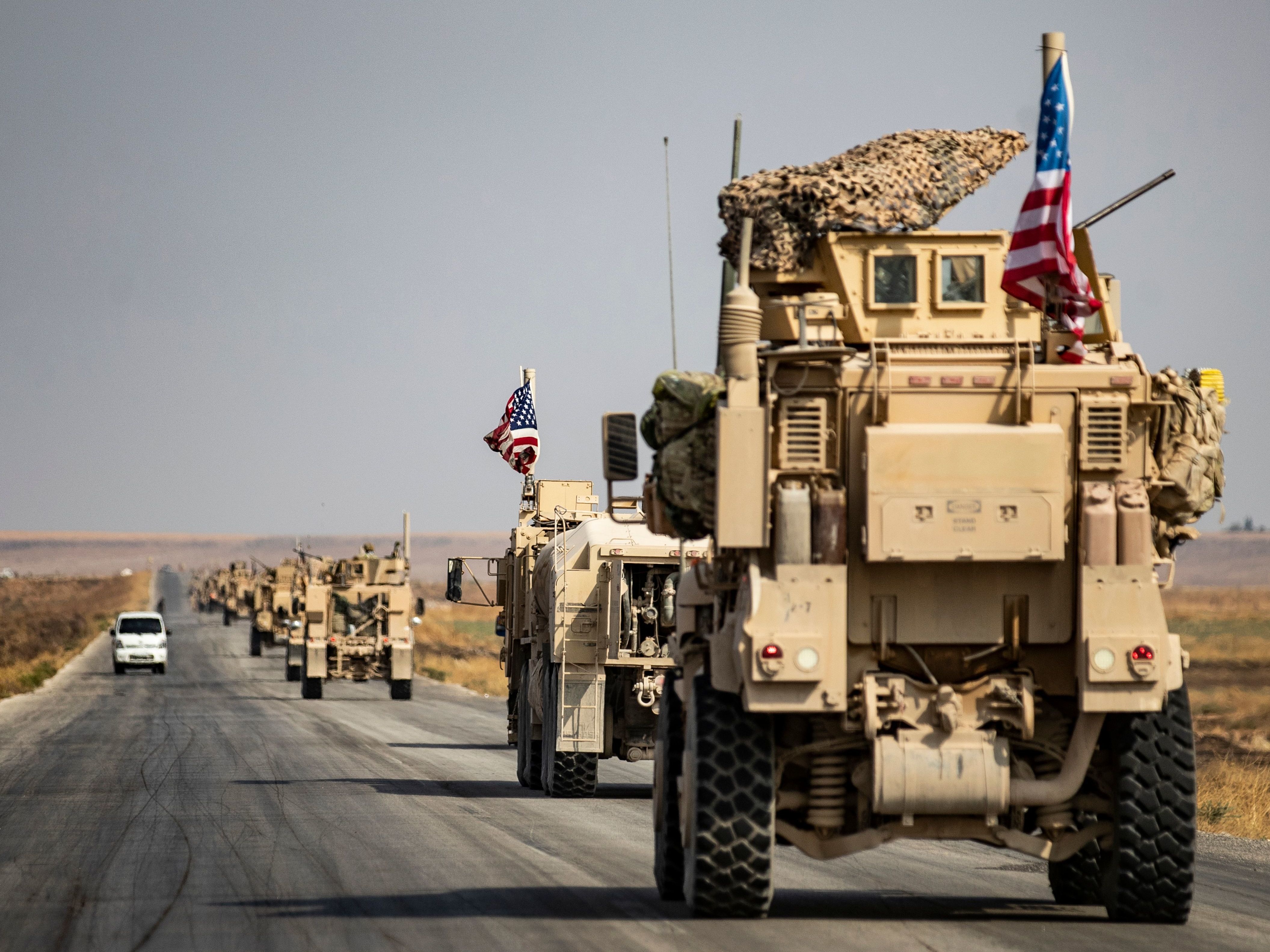 U.S. military vehicles drive on a road in the town of Tal Tamr on Sunday after pulling out of a base in northern Syria. Defense Secretary Mark Esper says some troops may remain in northeast Syria to secure oil fields. (AFP via Getty Images)