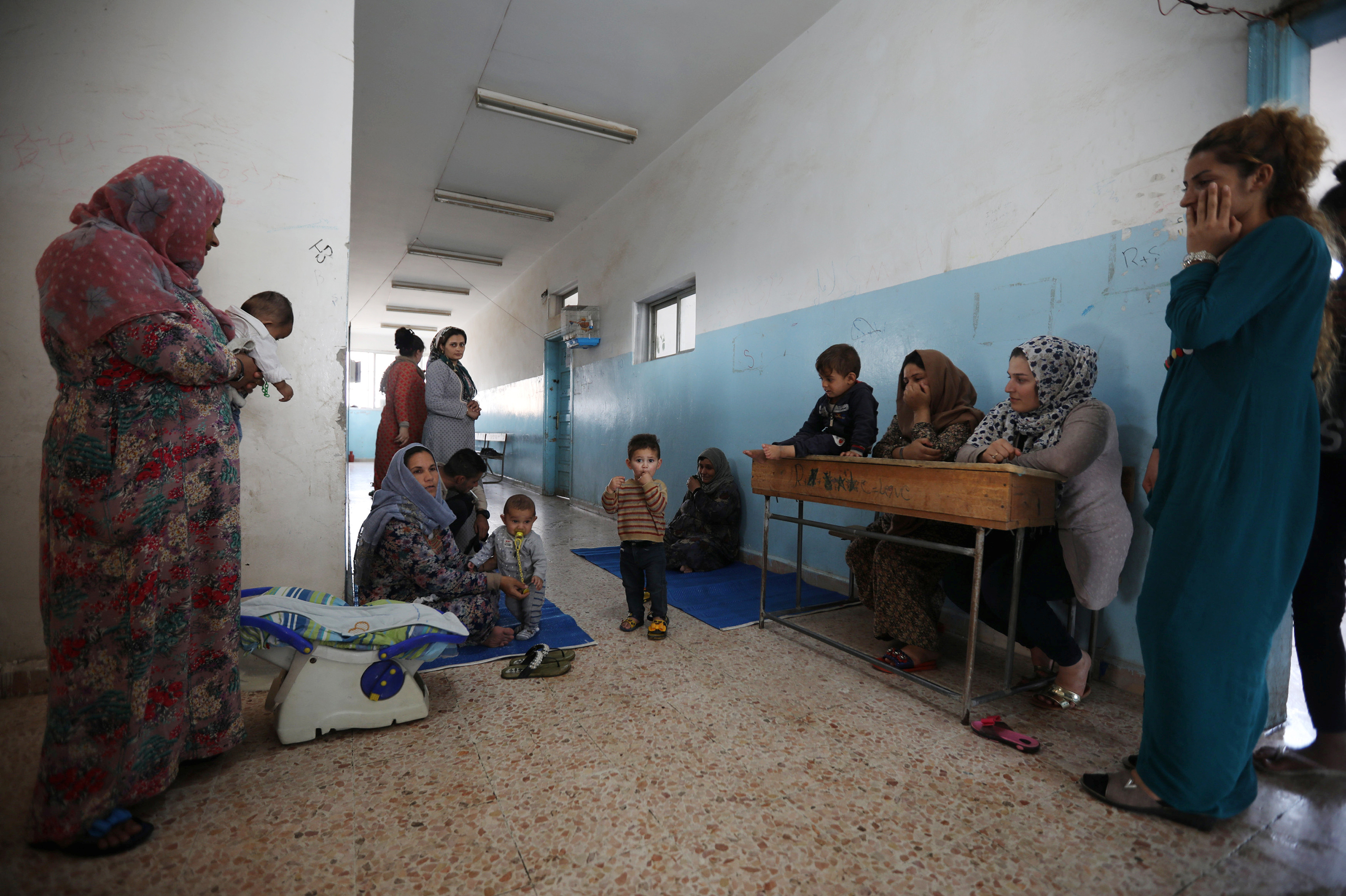 Displaced Kurdish and Arab women, who fled from violence after a Turkish offensive in northeastern Syria, sit with their children at a public school used as shelter where they now live in Hasakah, Syria. (Reuters)