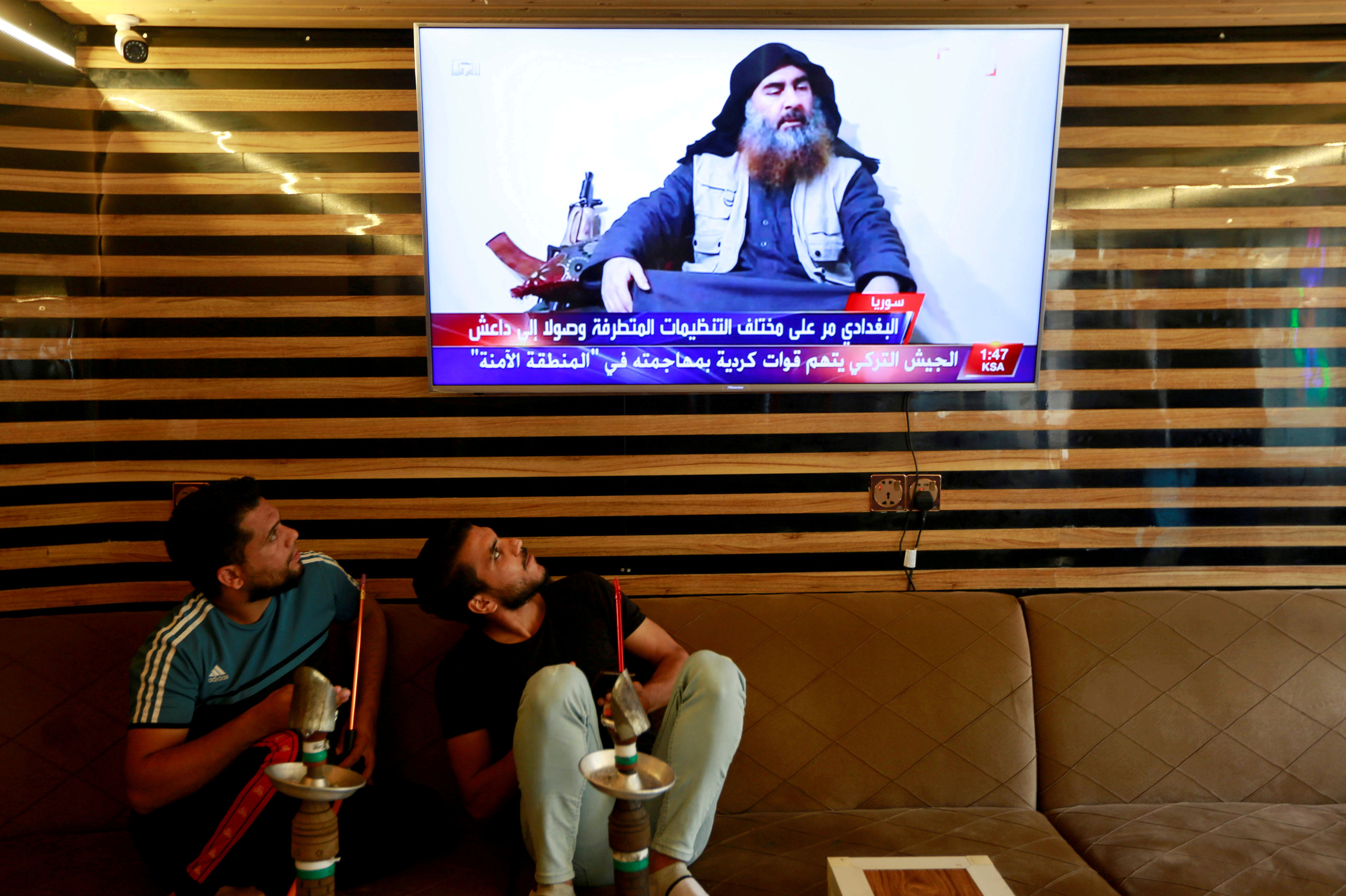 Iraqi youth watch the news about ISIS leader Abu Bakr al-Baghdadi's death, in Najaf, Iraq, on Sunday. (Reuters)