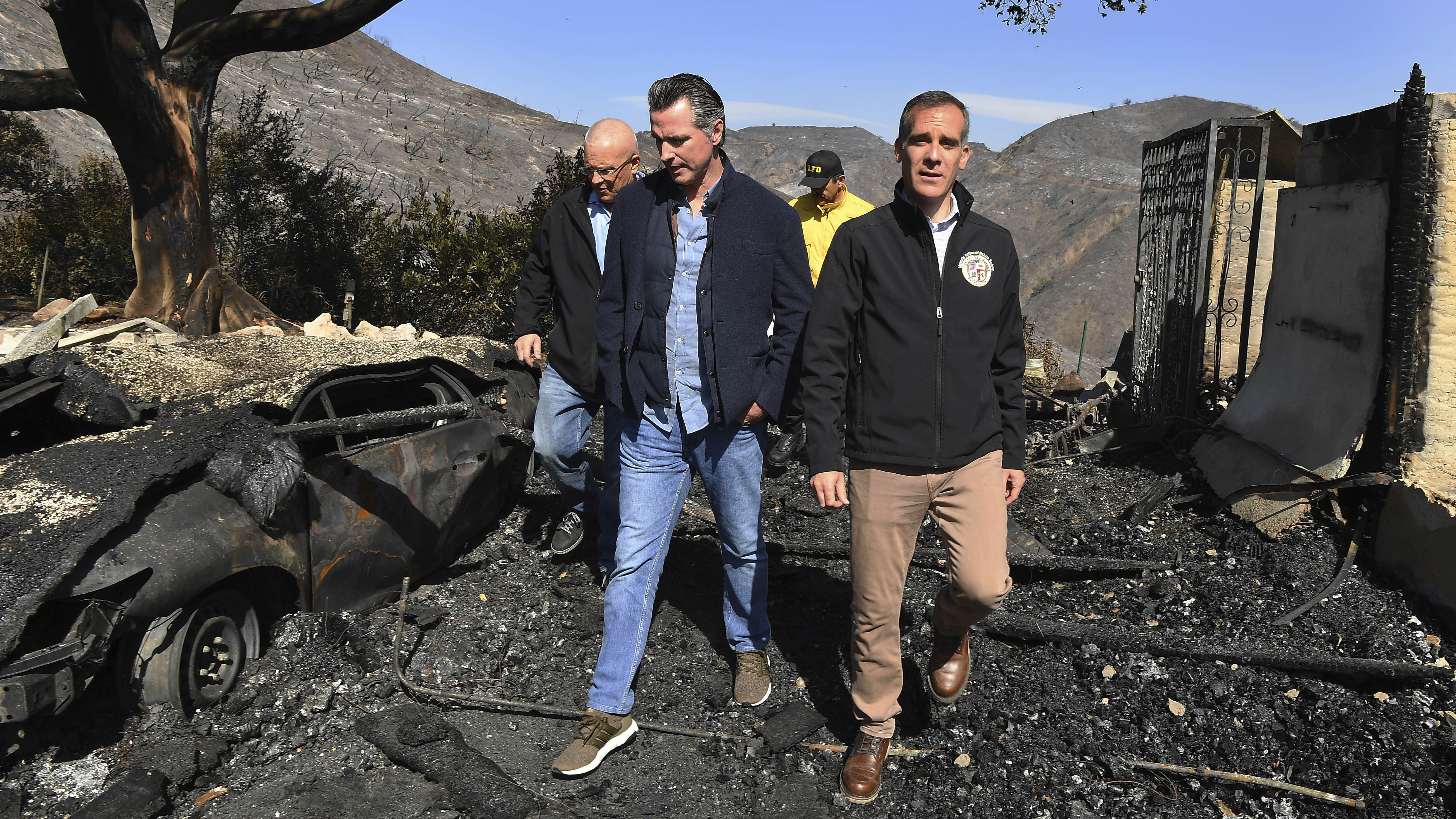 From left, LA City Councilman Mike Bonin, California Gov. Gavin Newsom and LA Mayor Eric Garcetti tour a burned home along in Brentwood, Calif., on Tuesday.