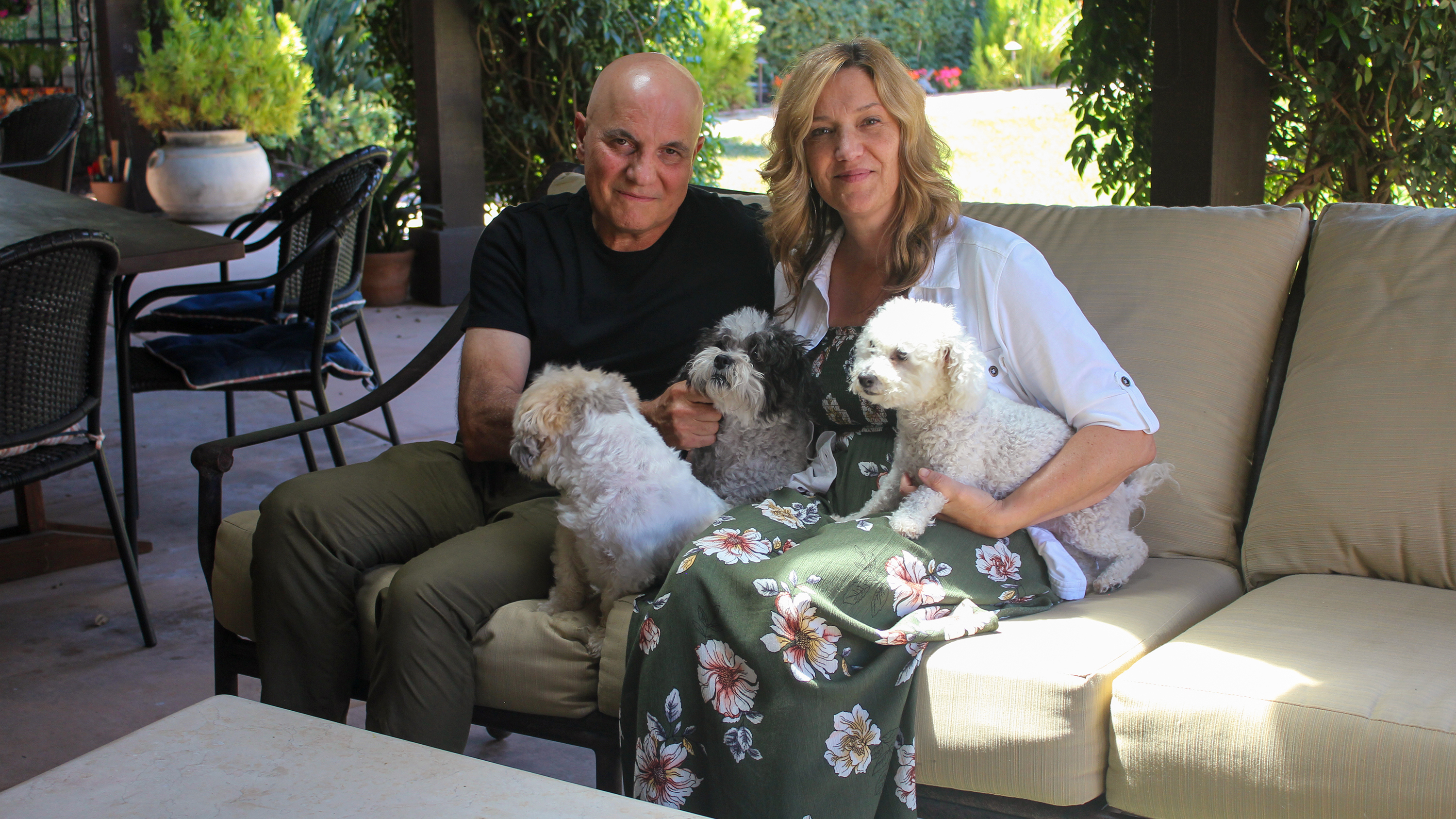 Tom and Dana Saputo sit in their backyard with their three dogs. Tom Saputo