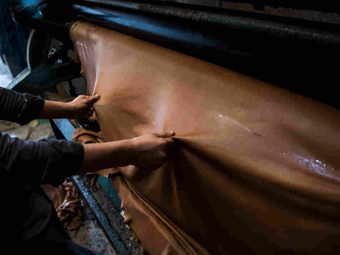 An employee handles a sheet of leather on a machine at a tannery in India. Photographer: Taylor Weidman/Bloomberg