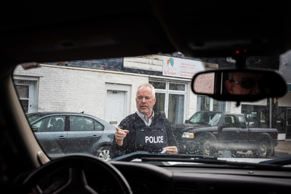 A member of the Royal Canadian Mounted Police holds Scott Wheeler's identification while asking another officer to collect the passports of Wheeler's passengers. Wheeler was pulled over for inadvertently driving into Canada from Canusa Avenue, which straddles the U.S.-Canadian border.