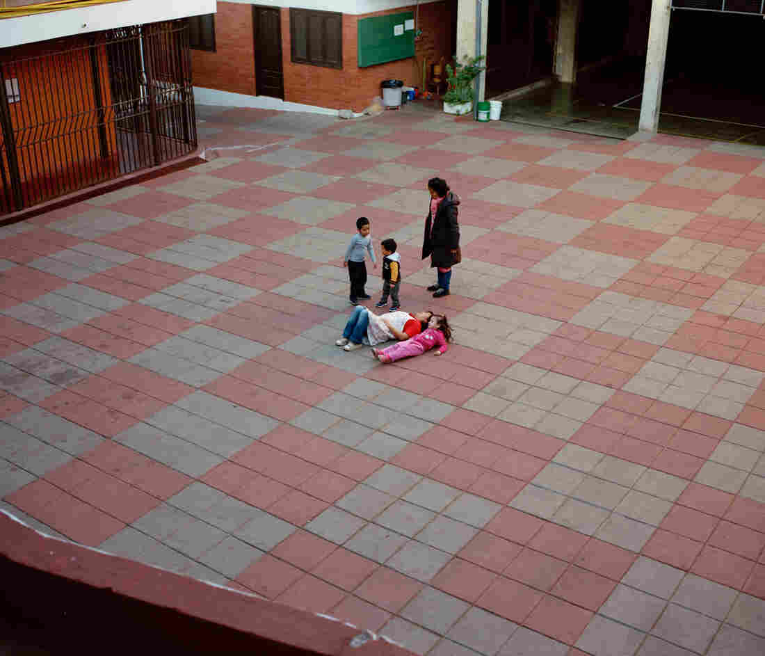 Kids play and lay on the ground in a courtyard.