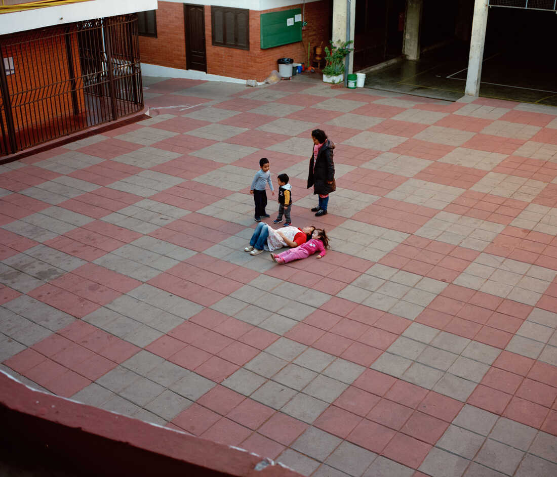 Kids play and lay on the ground in a courtyard.
