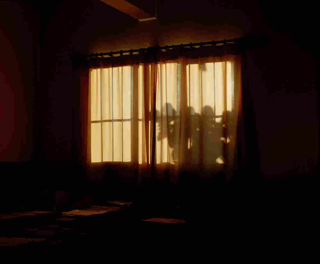 A curtain covers a window at sunset.