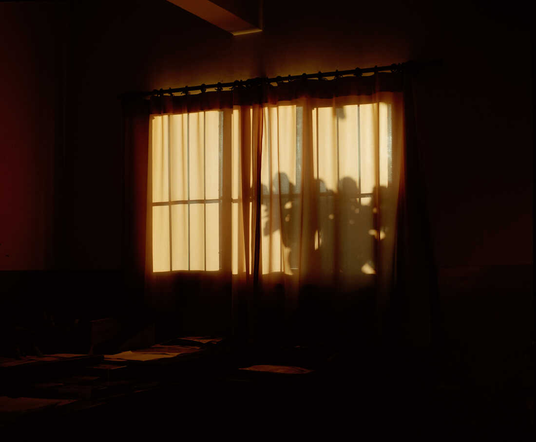 A curtain covers a window at sunset.