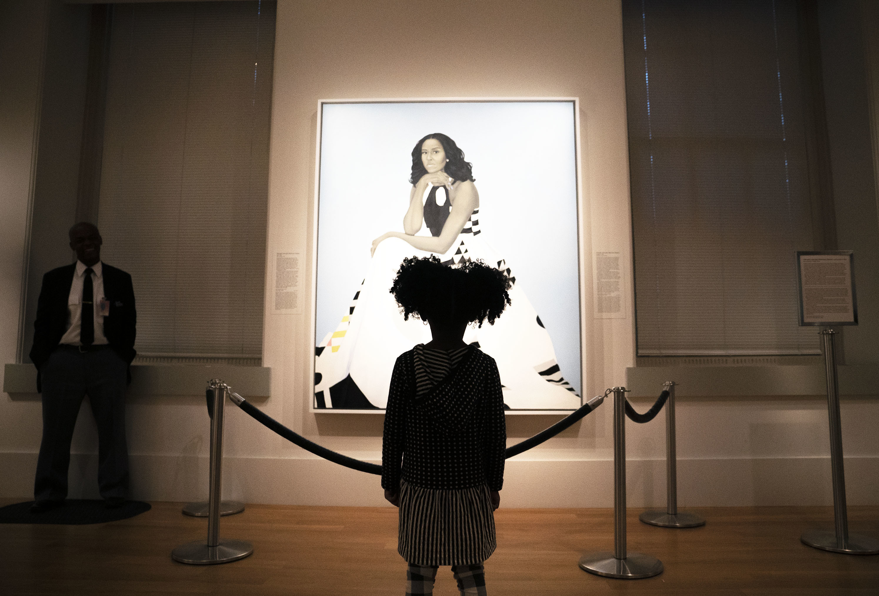 Parker Curry, 4, takes in Amy Sherald's painting of Michelle Obama in the National Portrait Gallery in Washington, D.C. Parker has co-authored a book with her mom called <em>Parker Looks Up: An Extraordinary Moment.</em> (NPR)