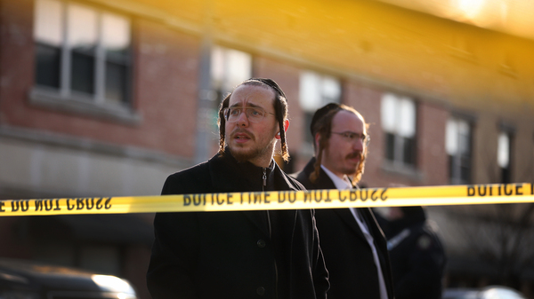 Two men look on as members of Jersey City's Jewish community gather outside the J.C. Kosher Supermarket on Wednesday. Six people, including the suspects and a local police officer, died Tuesday in what officials called a "targeted attack."