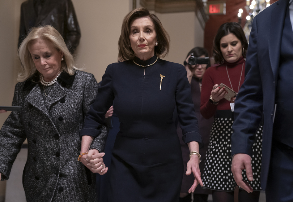 House Speaker Nancy Pelosi, D-Calif., holds hands with Rep. Debbie Dingell, D-Mich., as they walk to the chamber where the House begins debate on the impeachment charges against President Trump. (J. Scott Applewhite/AP)