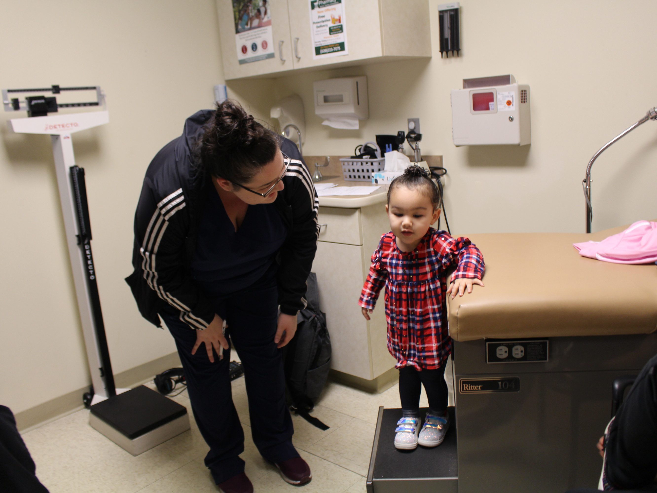 Eliza Oliver helps her daughter, Taelyn, step down from the exam table after a wellness check at the Community Health Center of Southeast Kansas in Fort Scott, Kan. The child's doctor now has a medical scribe to takes notes. The visit this time seemed more &quot;personal,&quot; Oliver says. (Kaiser Health News)