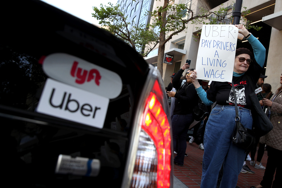 A supporter of ride-hail drivers holds a sign during a protest in front of Uber headquarters on May 8 in San Francisco. A new law in California aims to change how gig economy and other contract workers are classified. (Justin Sullivan/Getty Images)